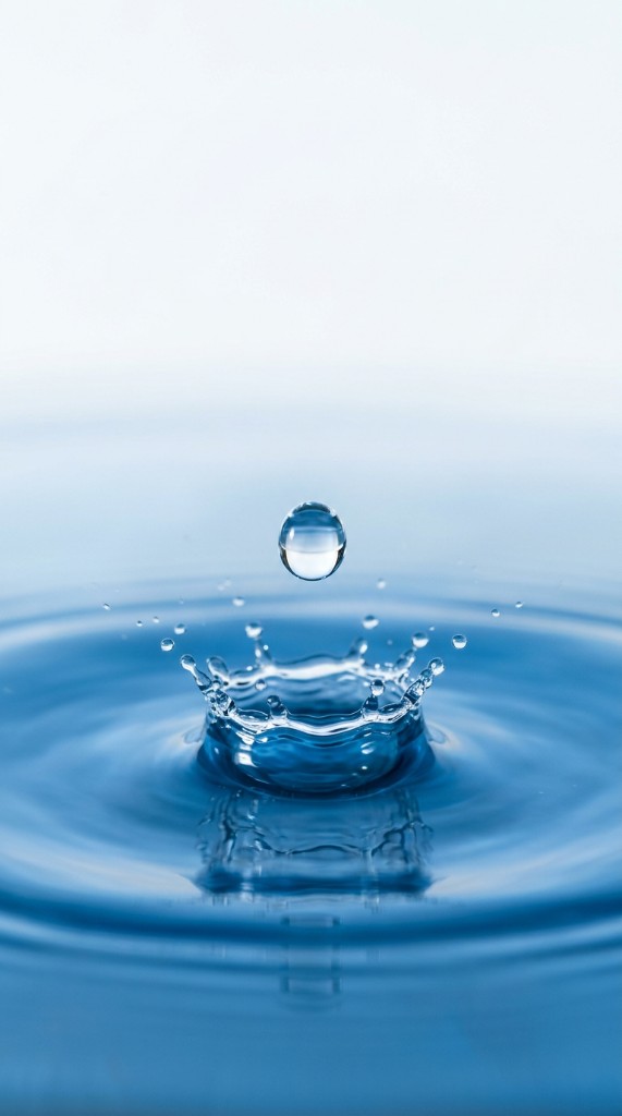 Single water droplet above a blue ripple splash