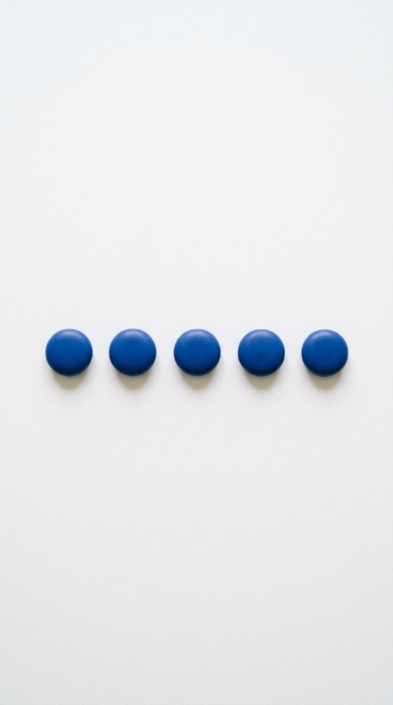 Five small blue objects arranged in a row on a white surface